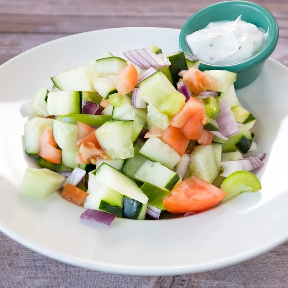 A Bengal Tiger Cuisine Of India kachumber salad with diced cucumbers, tomatoes, and red onions, served with raita.